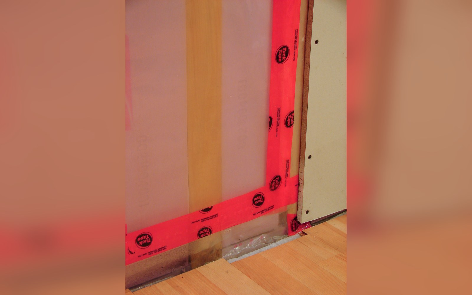 Hands pressing airtightness tape into the junction between a membrane and a window frame